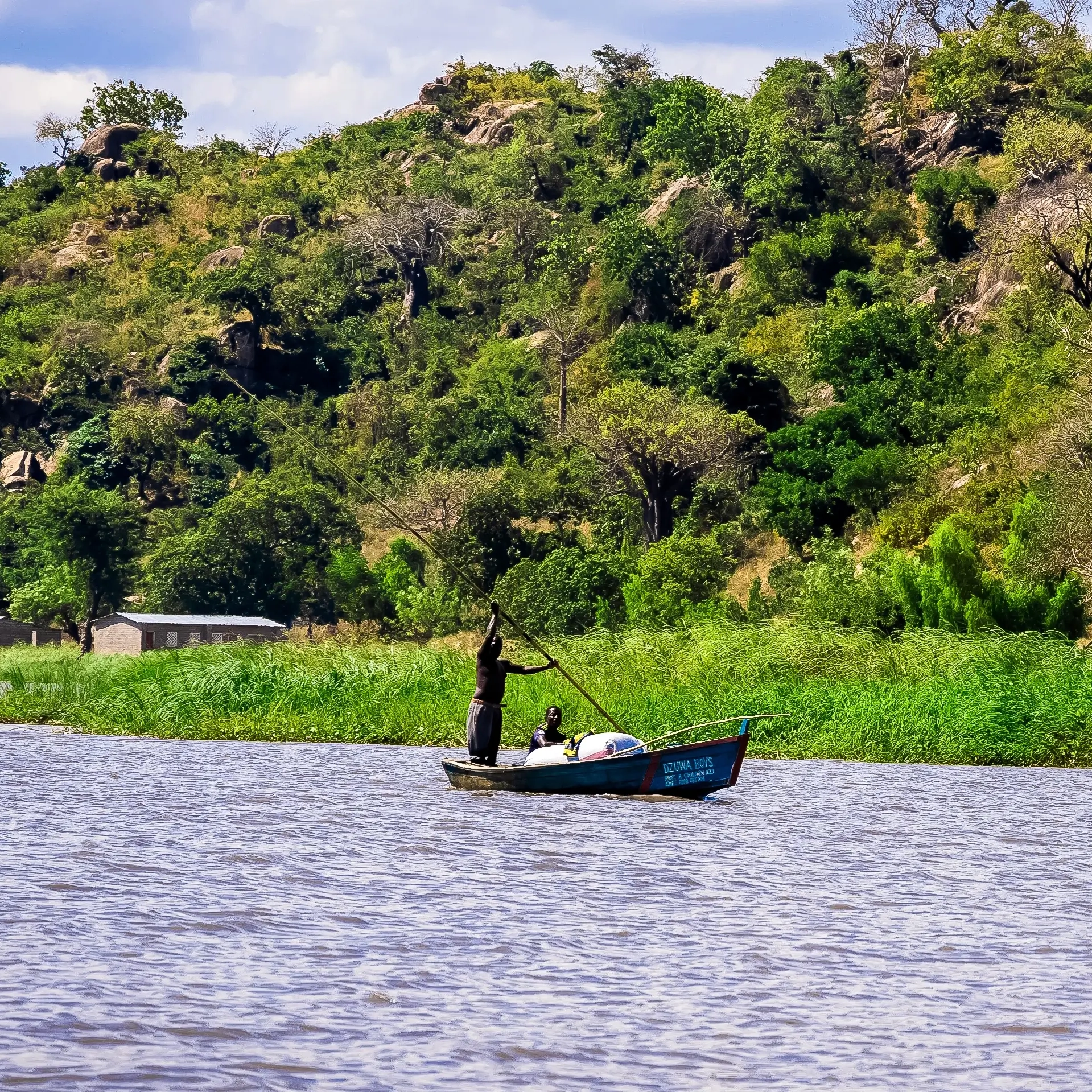 A boat in a serene mountainous river with lots of greenery.