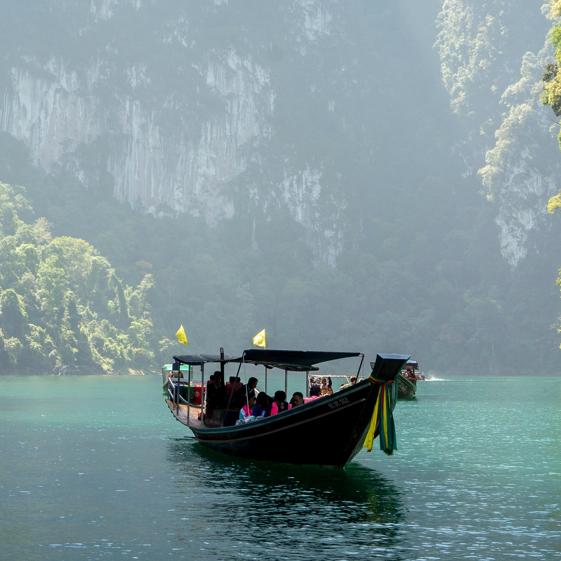 A boat in a serene mountainous river with lots of greenery.